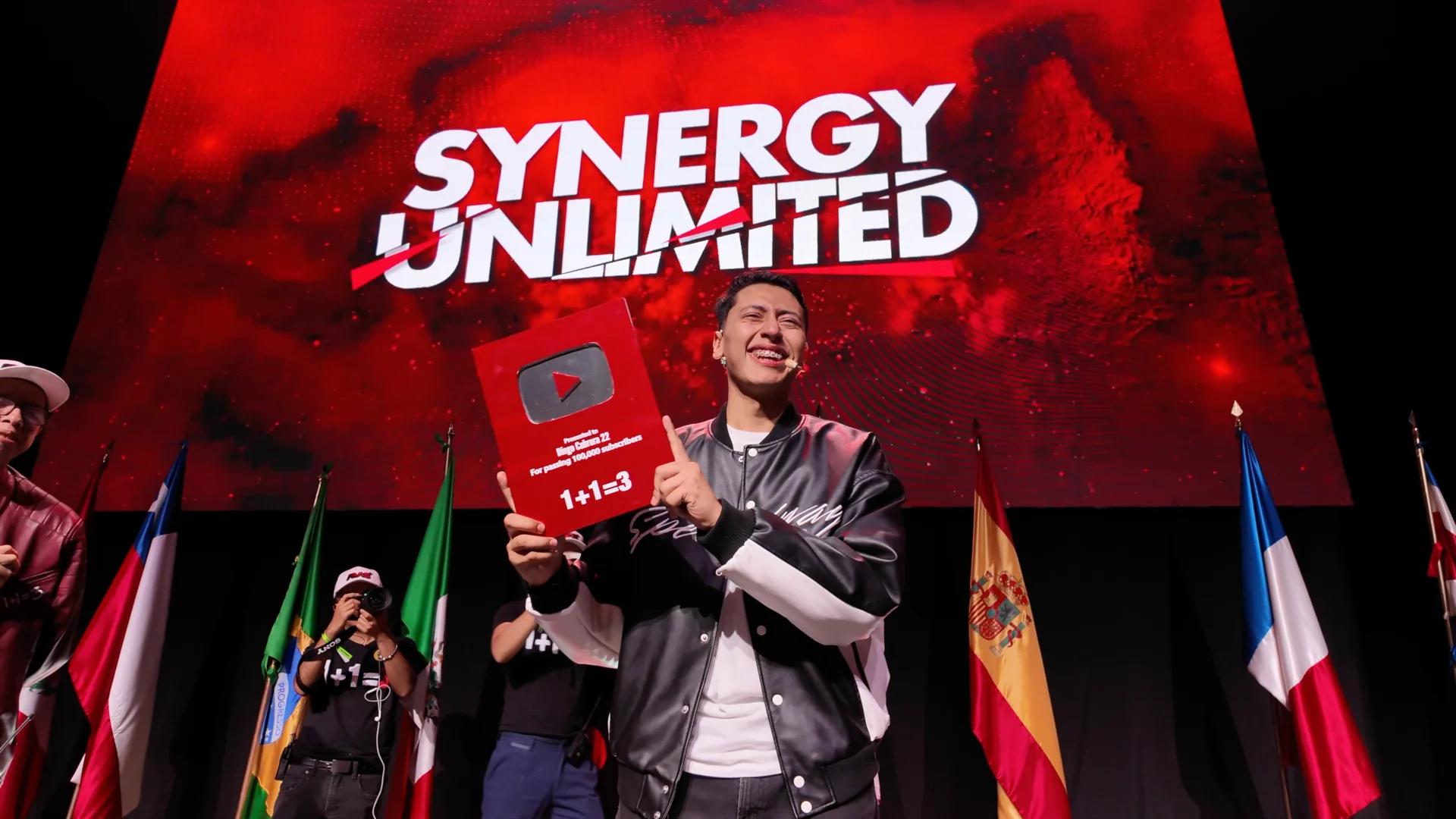 Diego Cabrera con su reconocimiento de YouTube frente a la pantalla gigante de Synergy Unlimited